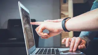 Dos personas revisando información técnica en un ordenador portátil durante una reunión de trabajo.
