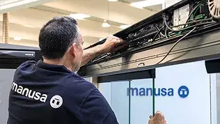 Técnico de Manusa realizando labores de mantenimiento en el mecanismo superior de una puerta automática.