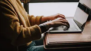 Persona trabajando con un ordenador portátil en tareas administrativas y de gestión técnica.