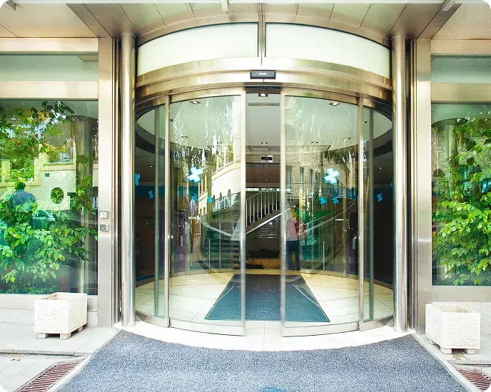 Puerta automática giratoria de vidrio en entrada de edificio