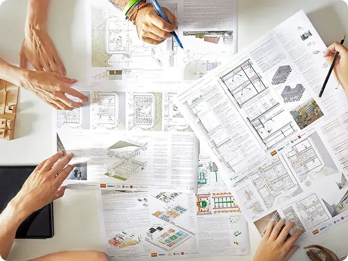 Equipo técnico revisando planos y documentación de un proyecto de puertas automáticas sobre una mesa de trabajo.