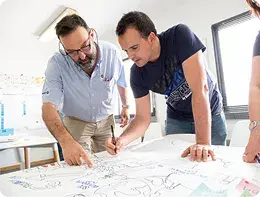 Dos técnicos revisando planos sobre una mesa.